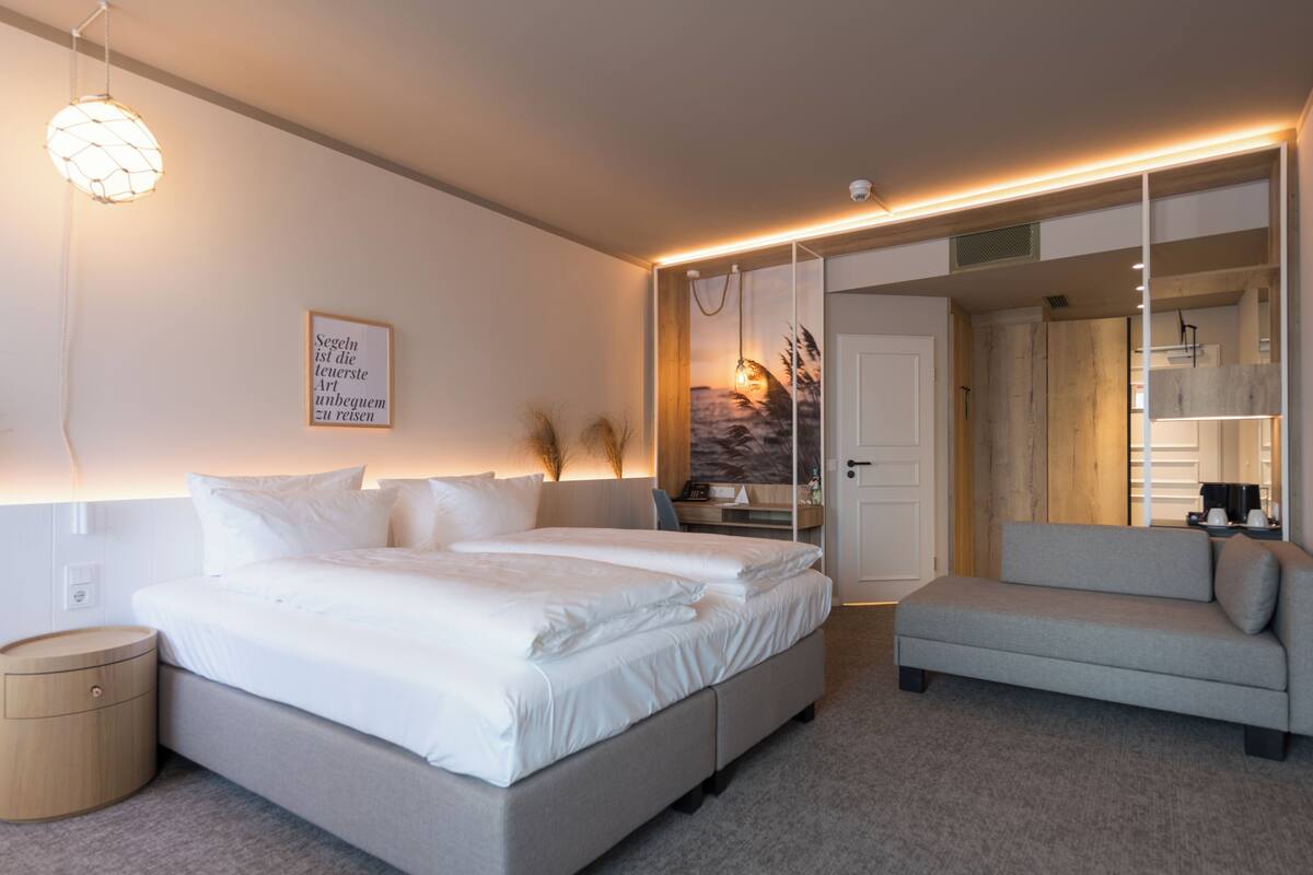 A modern bedroom with a large bed, a sofa, and a walk-in closet.