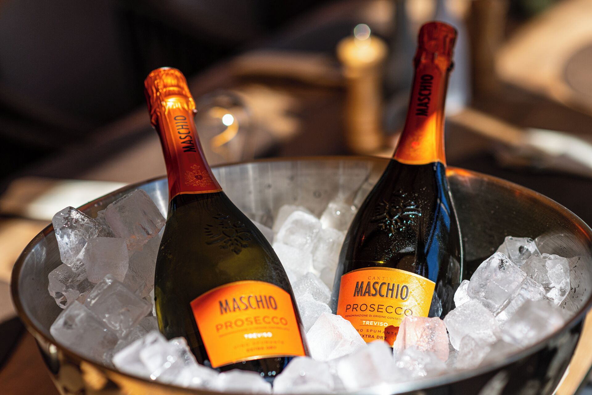 Two bottles of Maschio Prosecco champagne in a metal bucket filled with ice cubes.