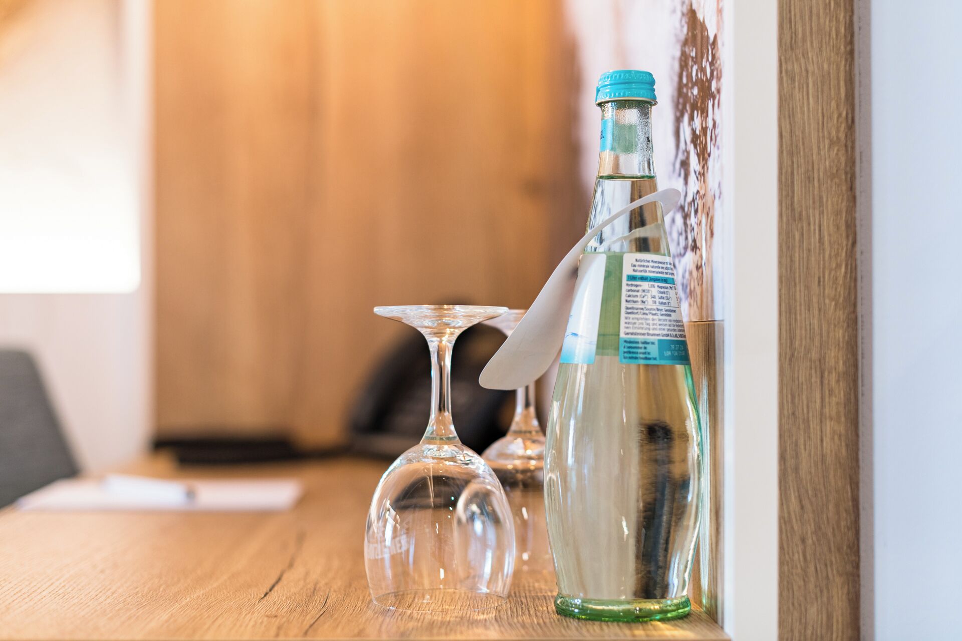 Ein Holztisch mit einer Wasserflasche, einem Glas und einem Messer.