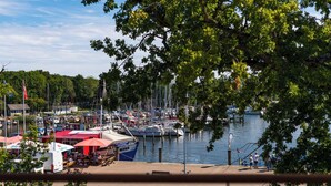 A marina with boats docked, a café with outdoor seating, and a view of the water. - Hafenhotel zu Putbus (Putbus)