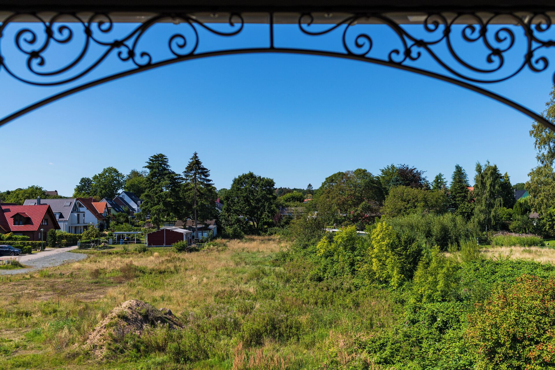 Un paisaje rural con casas, árboles y un arco de metal.