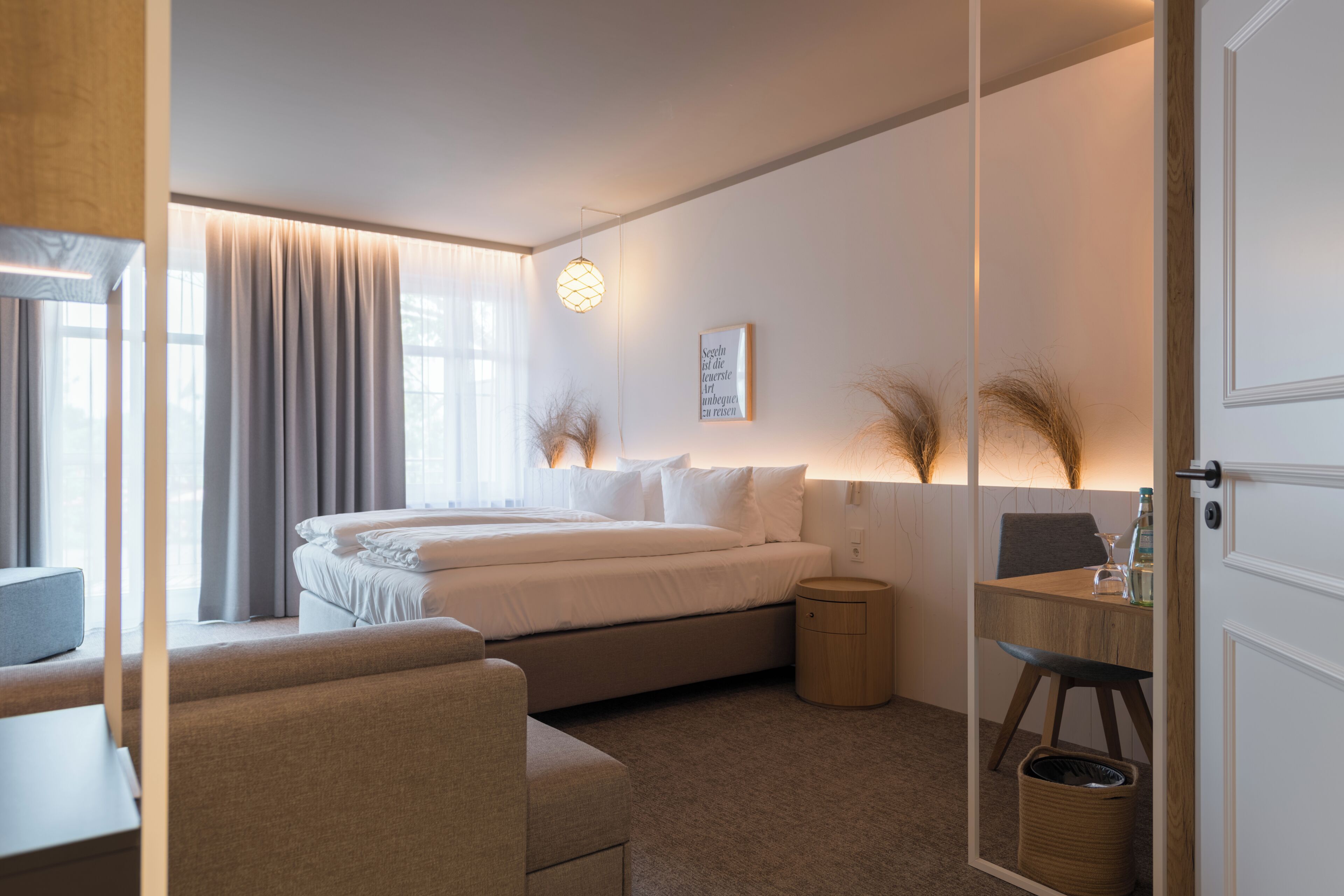 Ein modernes Hotelzimmer mit einem großen Bett, Nachttischen, einem Schreibtisch und einem Sessel.