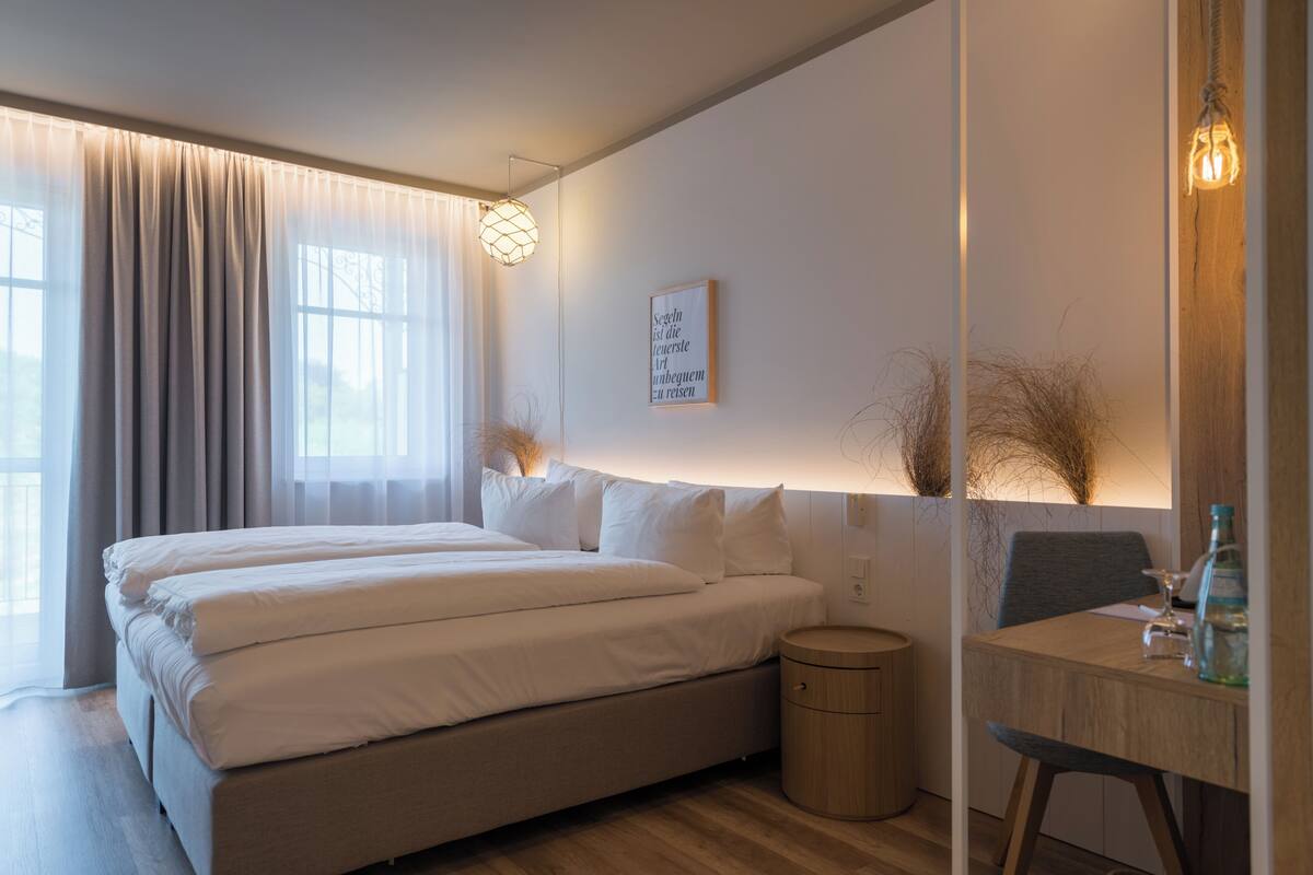 A modern bedroom with a bed, bedside table, lamp, and a framed quote on the wall.