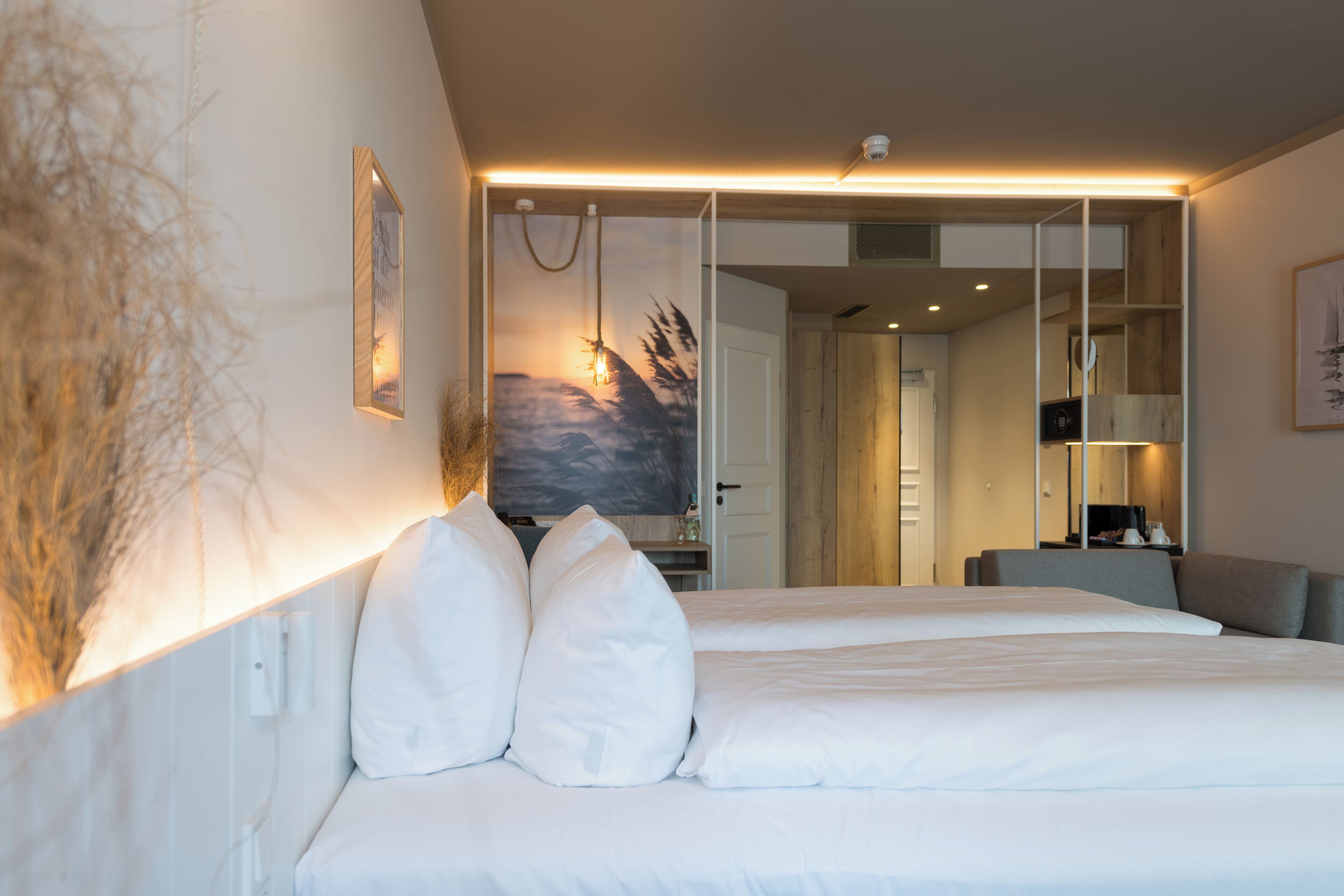 Una habitación de hotel moderna con una cama grande, un cuadro en la pared y vistas a la habitación contigua.