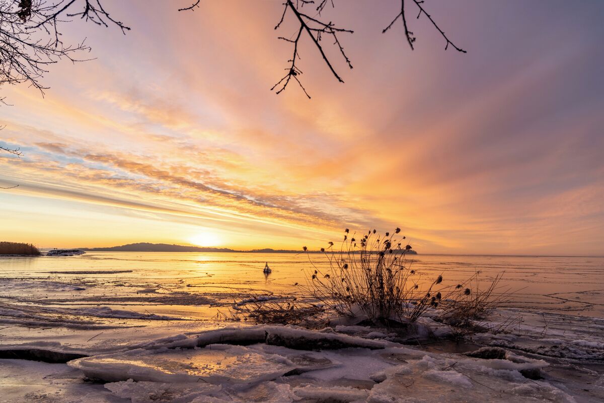 A frozen lake with ice formations and a sunset in the background.
