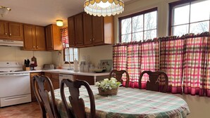 A kitchen with wooden cabinets, a stove, and a dining table with chairs.