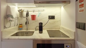A compact kitchen with two sinks, a built-in stove, and a microwave. There is a hanging rack with utensils and a red bucket. - FLH Porto Ribeira Typical Studio (Oporto)