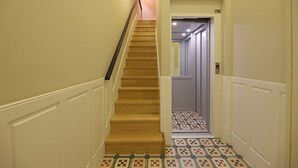 A staircase with wooden steps and white walls, leading to a door with a patterned floor. - FLH Porto Ribeira Typical Studio (Oporto)
