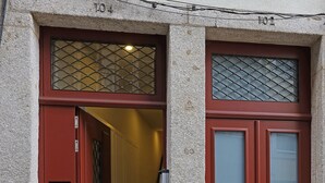A building entrance with two red doors, a metal mail slot, and a cobblestone ground. - FLH Porto Ribeira Typical Studio (Oporto)