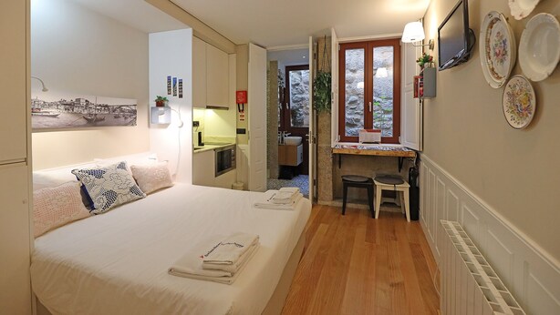 A compact hotel room with a bed, a desk, and a small kitchenette. - FLH Porto Ribeira Typical Studio (Oporto)