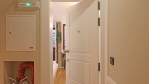 A hallway with a white door leading to a bedroom, a red pipe, and a vent on the ceiling. - FLH Porto Ribeira Typical Studio (Oporto)
