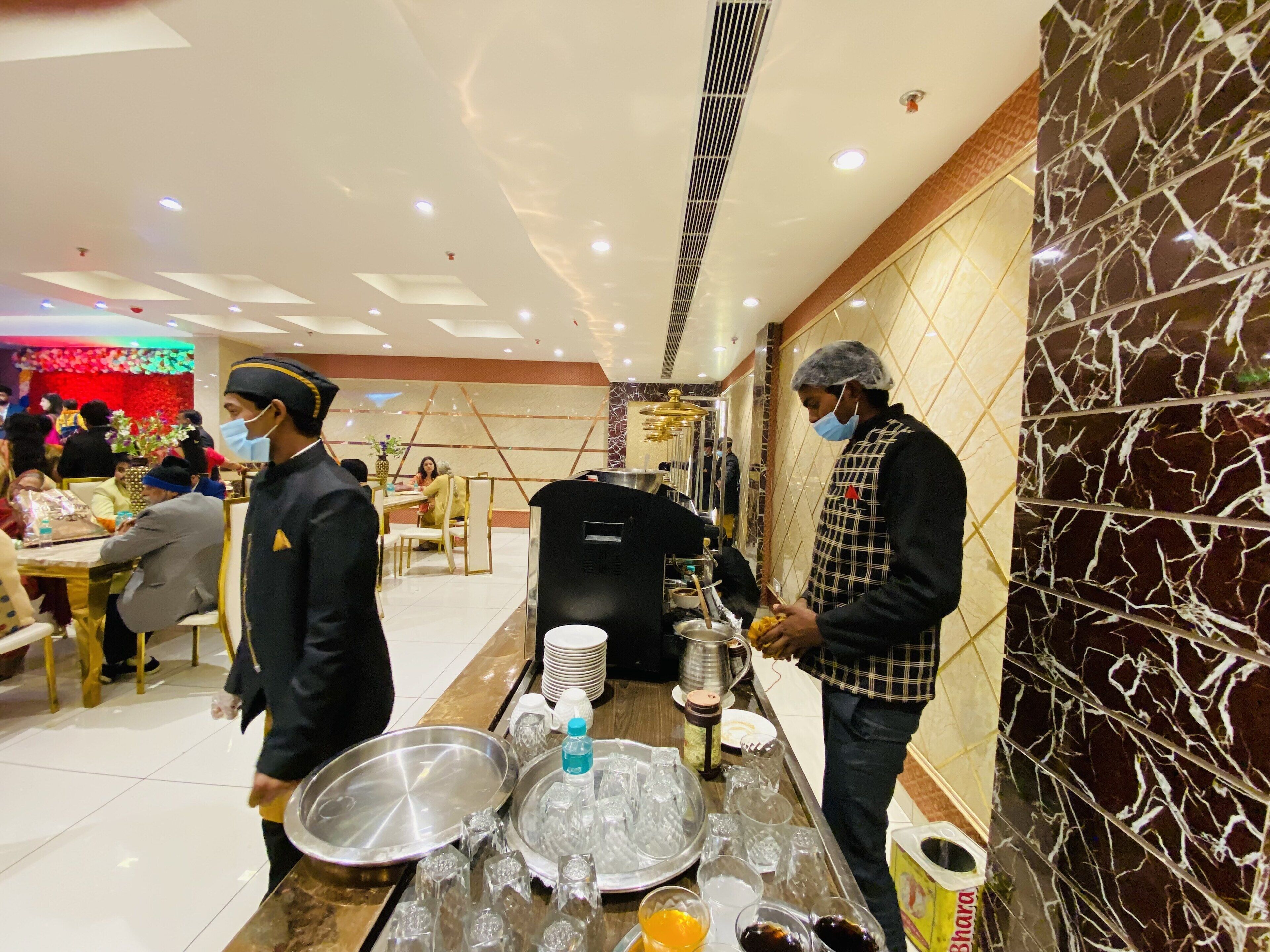 A buffet setup with a counter, plates, glasses, and a beverage dispenser.