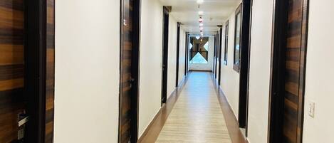 A long, narrow hallway with wooden doors on both sides and a carpeted floor.