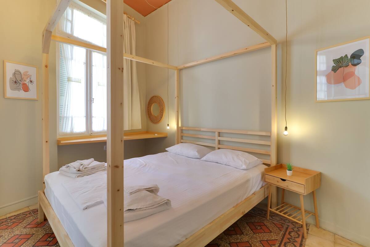 A wooden bunk bed with a headboard, a bedside table with a plant, and a wall-mounted mirror.