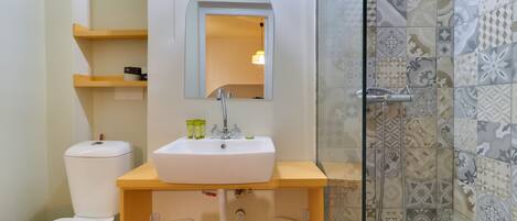 A bathroom with a white sink, a mirror, a toilet, and a shower area.