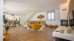 Un salon moderne avec un canapé, un fauteuil jaune et un coin repas comprenant une table et des chaises.
