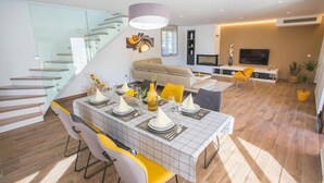 Un salon moderne comprenant un coin repas, un canapé, un téléviseur et un escalier.