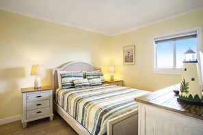 A bedroom with a bed, two bedside tables, a nightstand, a lamp, a framed picture, and a window with a view. - 0710 Waters Edge Resort 1 Bedroom Condo by RedAwning (Murrells Inlet)