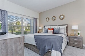 A modern bedroom with a large bed, bedside tables, and a window with blinds. - Champions Gate 4 Bedroom Townhouse by Redawning (Davenport)