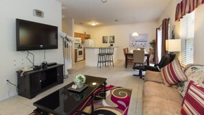 A living room with a television, a coffee table, a sofa, and a dining area with chairs and a table. - 3000yl 4 Bedroom Townhouse by RedAwning (Kissimmee)