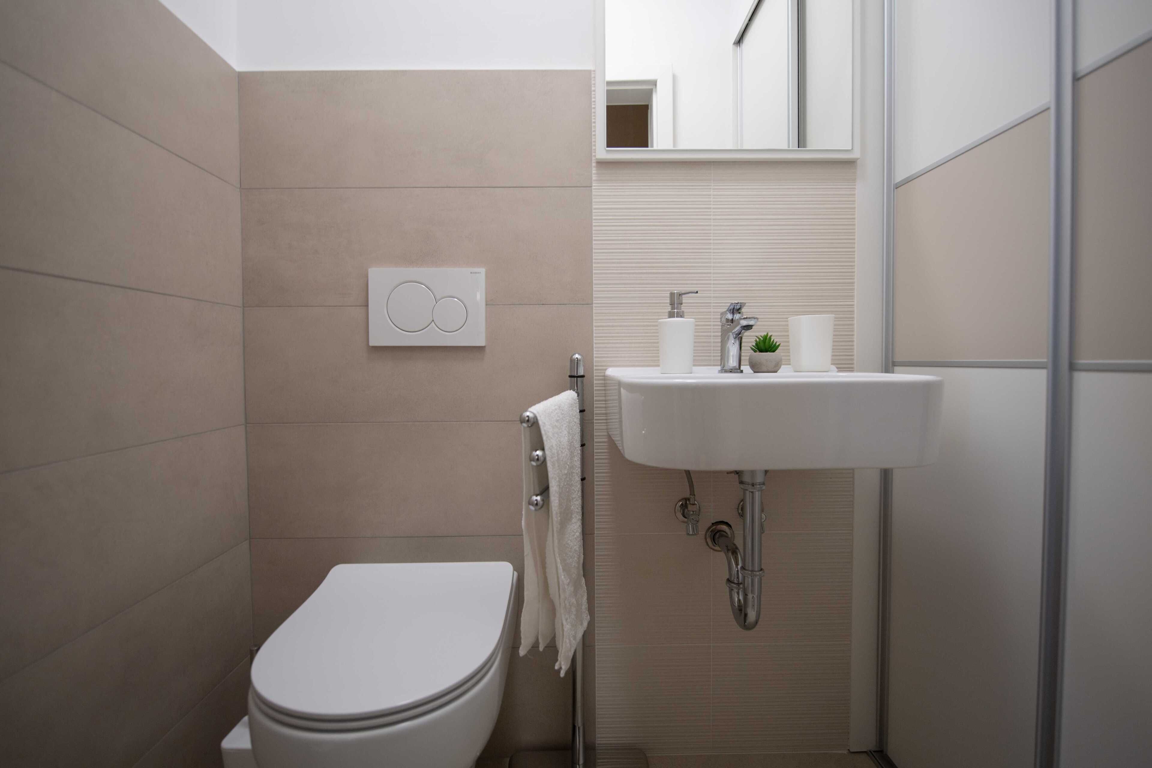 A modern bathroom with a toilet, sink, and towel rack.