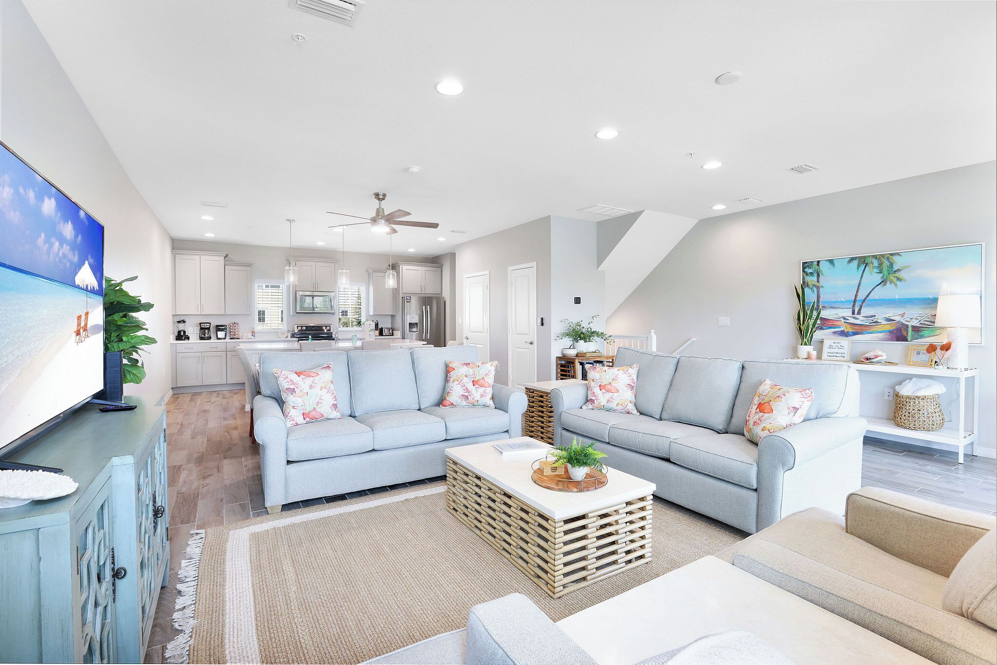 A modern living room with a light blue sofa, a coffee table, and a television on a stand.