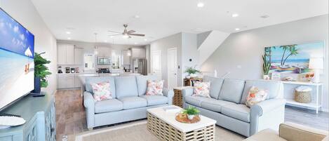 A modern living room with a light blue sofa, a coffee table, and a television on a stand.