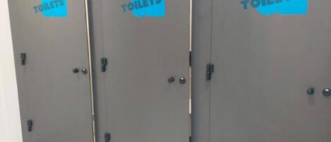 Three grey doors with blue icons and the word "TOILETS" on them, indicating a restroom area.