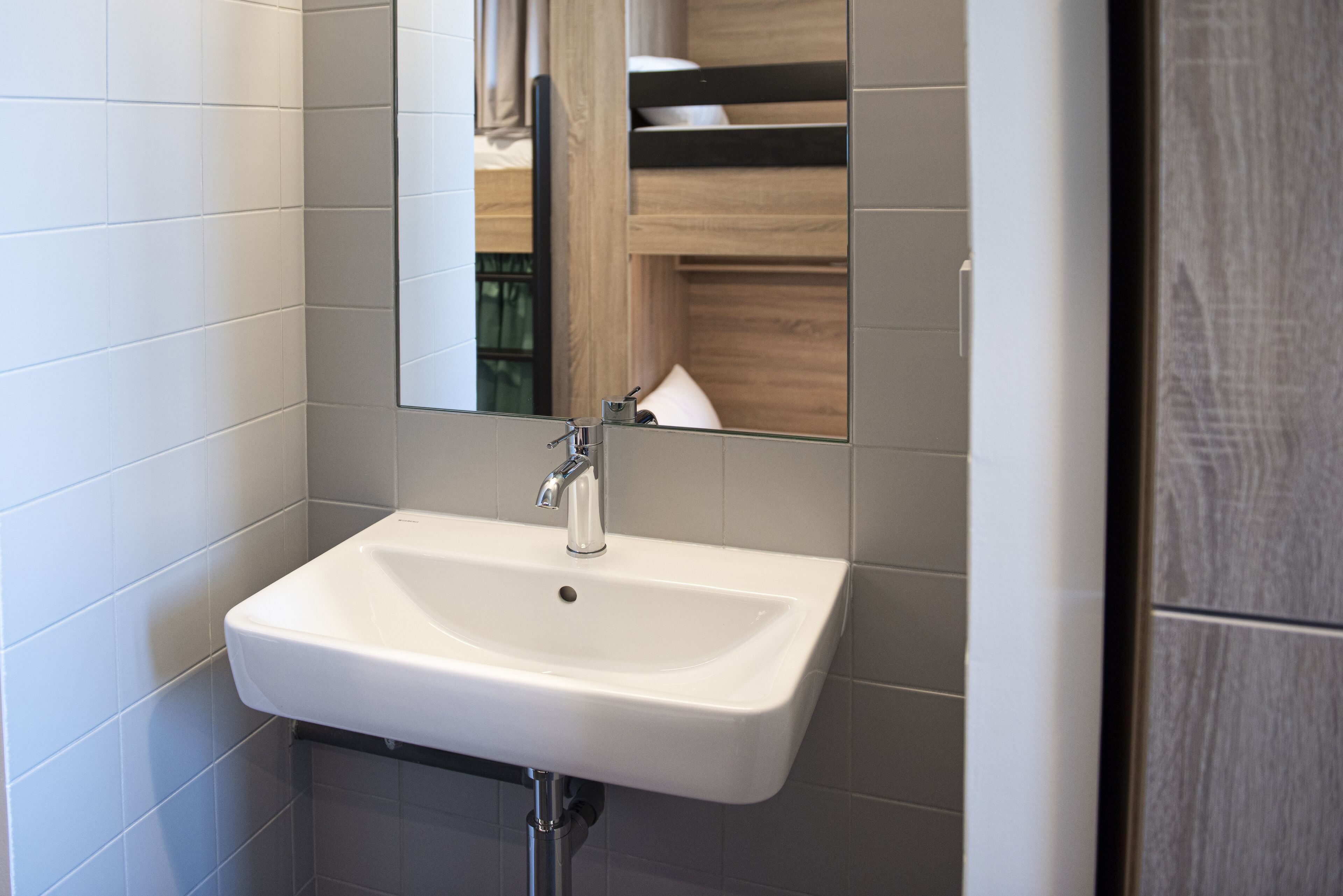 Une salle de bain moderne avec un lavabo blanc, un miroir et des étagères en bois.
