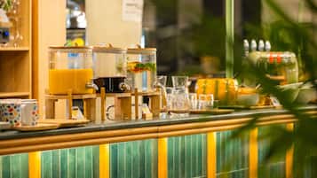 Un espace bar avec un comptoir, divers récipients en verre et un mur recouvert de carreaux verts.