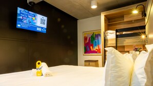 A hotel room with a bed, a TV mounted on the wall, a colorful painting, and a wooden bunk bed. - The People Paris Marais (Paris)