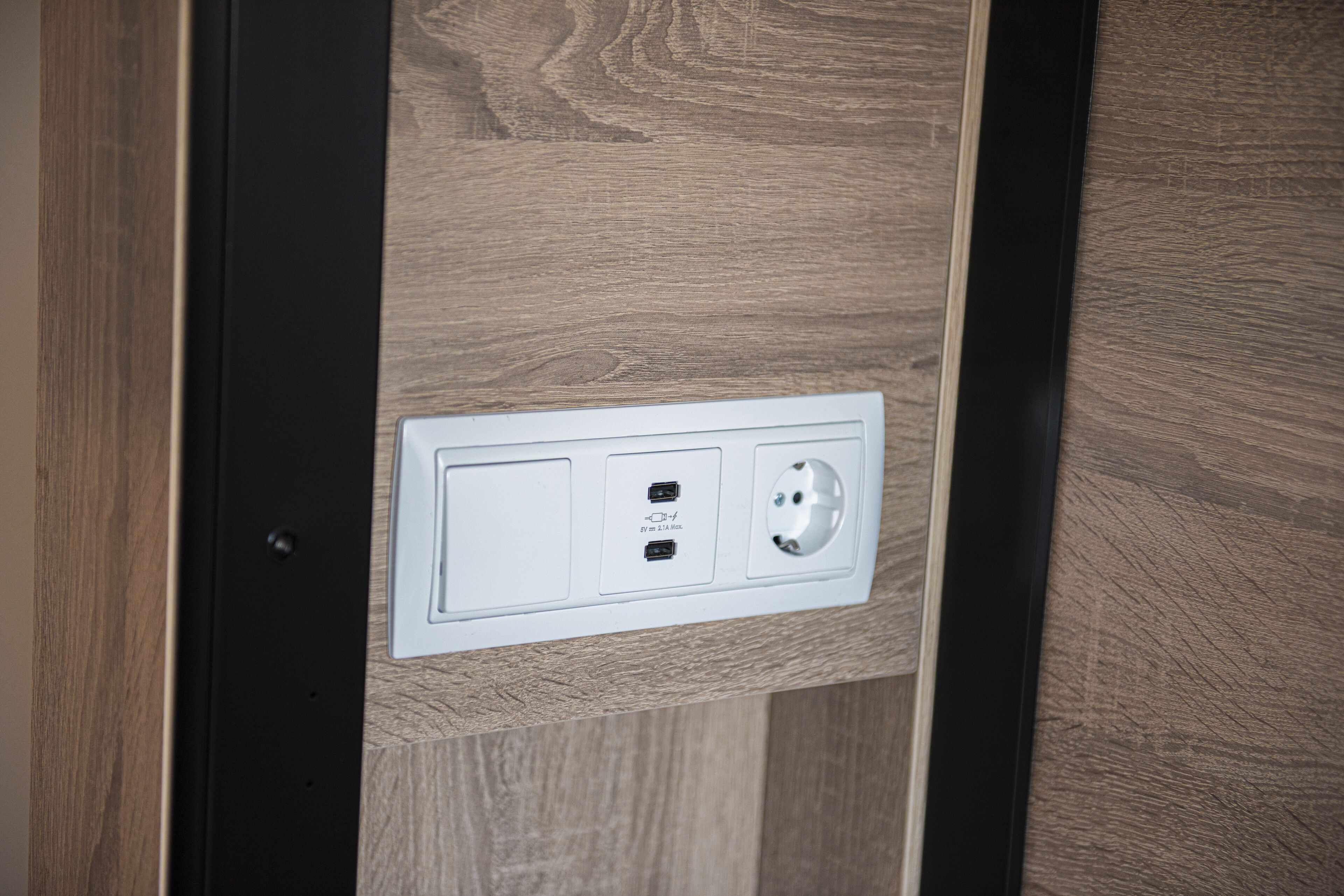 A wall-mounted electrical outlet with two USB ports and a standard plug socket.