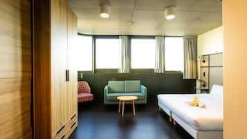 Una habitación de hotel con una cama, una mesita, un sofá y un armario.
