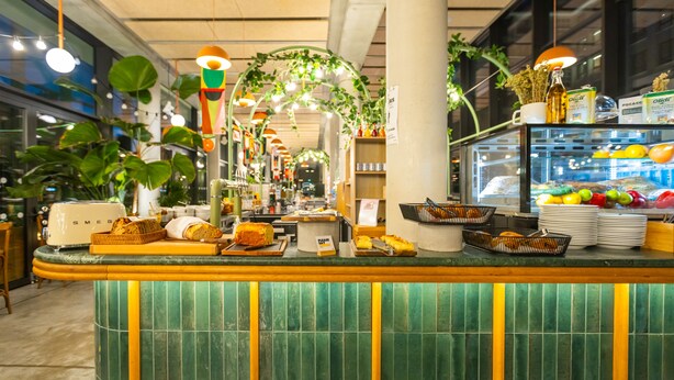 A breakfast bar with a variety of food items and a glass display case with fruits and beverages. - The People Paris Marais (Paris)