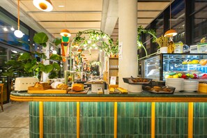 A breakfast bar with a variety of food items and a glass display case with fruits and beverages. - The People Paris Marais (Paris)