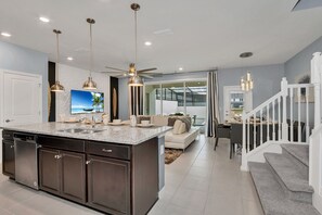A modern kitchen with a large island, built-in appliances, pendant lighting, and a dining area with a view.