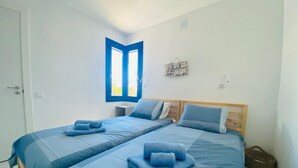 Un dormitorio con dos camas, una ventana y un adorno en la pared.