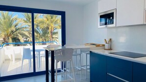 Una cocina moderna con un amplio ventanal, taburetes blancos y una encimera azul.