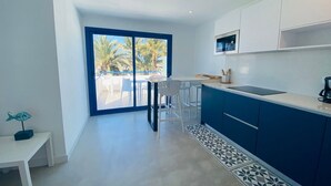 Una cocina moderna con un ventanal grande, comedor blanco y armarios azules.