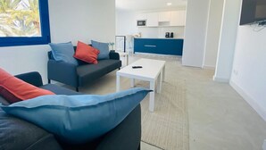 Una sala moderna con un sofá, una mesa de centro y una cocina al fondo.