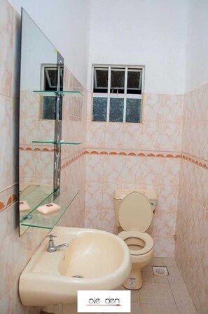 Un bagno con lavandino, specchio, WC e una finestra.