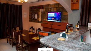Un'accogliente sala da pranzo con parete in pietra, televisore sopra un caminetto e bancone bar con top in marmo.