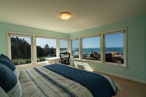 Une chambre avec un grand lit, un bureau et une vue sur l’océan.