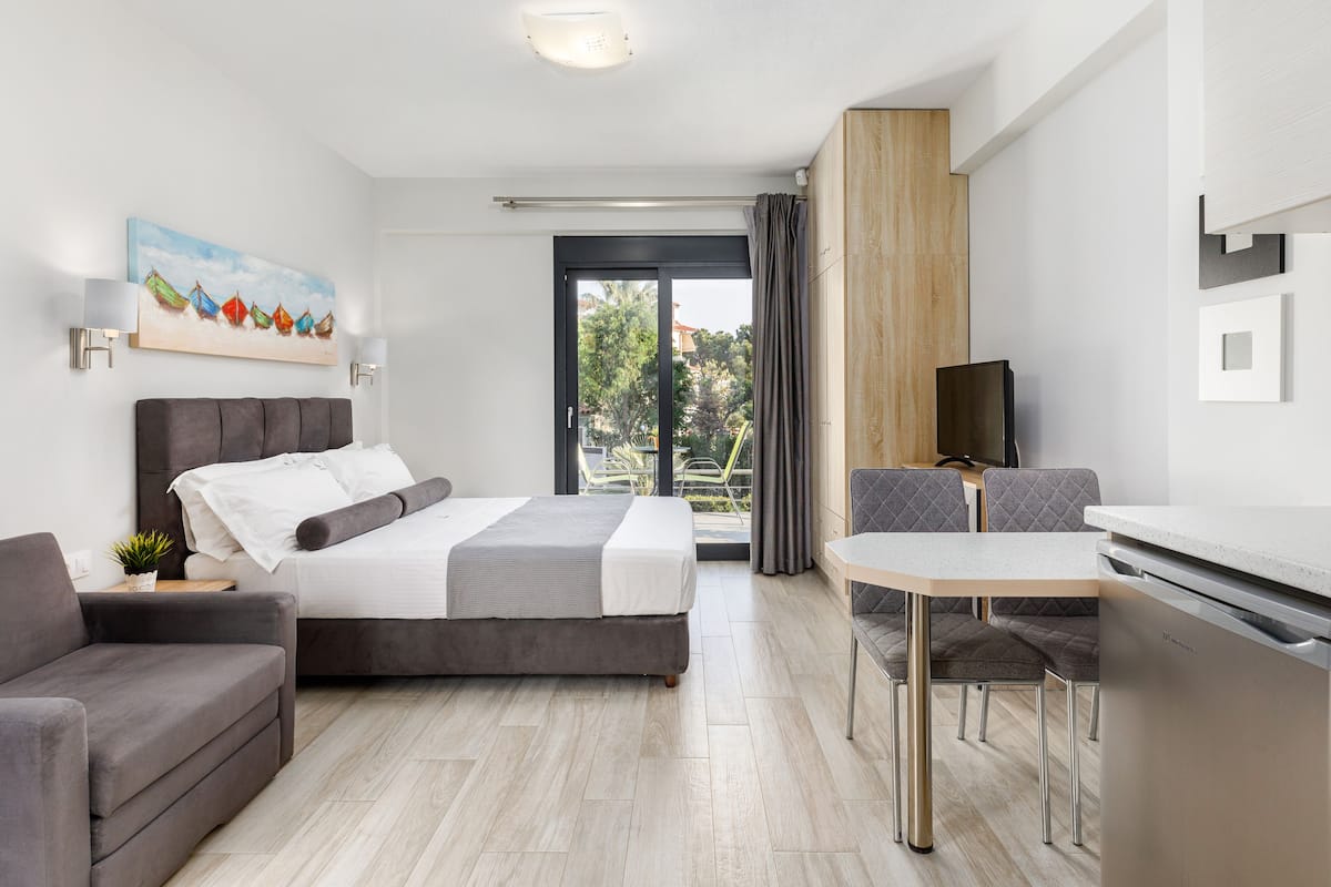 Una habitación de hotel moderna con una cama, una mesa de comedor, un sofá y un televisor.
