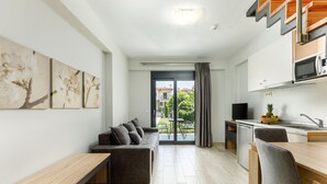 Una sala moderna con un sofá, una mesa de madera y una zona de cocina con microondas.