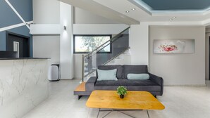 Una sala moderna con un sofá, una mesa de centro y una escalera.