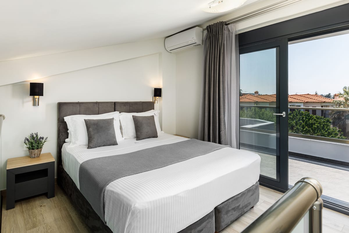 Un dormitorio moderno con una cama grande, una mesita de noche, una planta en maceta y vistas de la ciudad a través de un ventanal amplio.