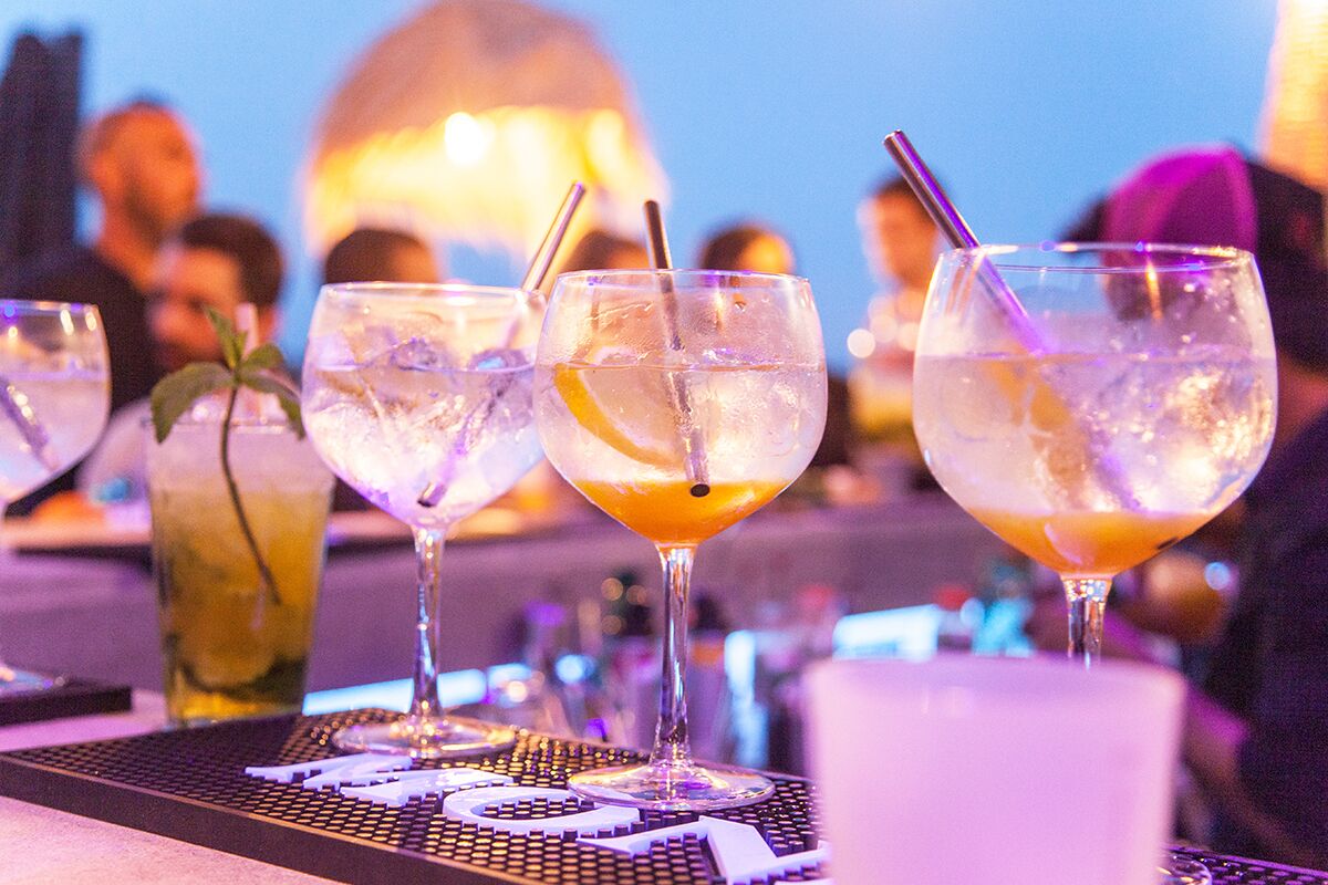 Een bar met glazen diverse drankjes, ijs en garnering.
