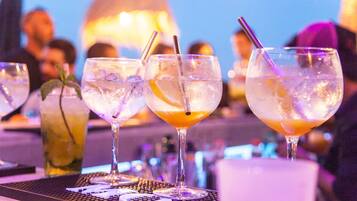 Een bar met glazen diverse drankjes, ijs en garnering.