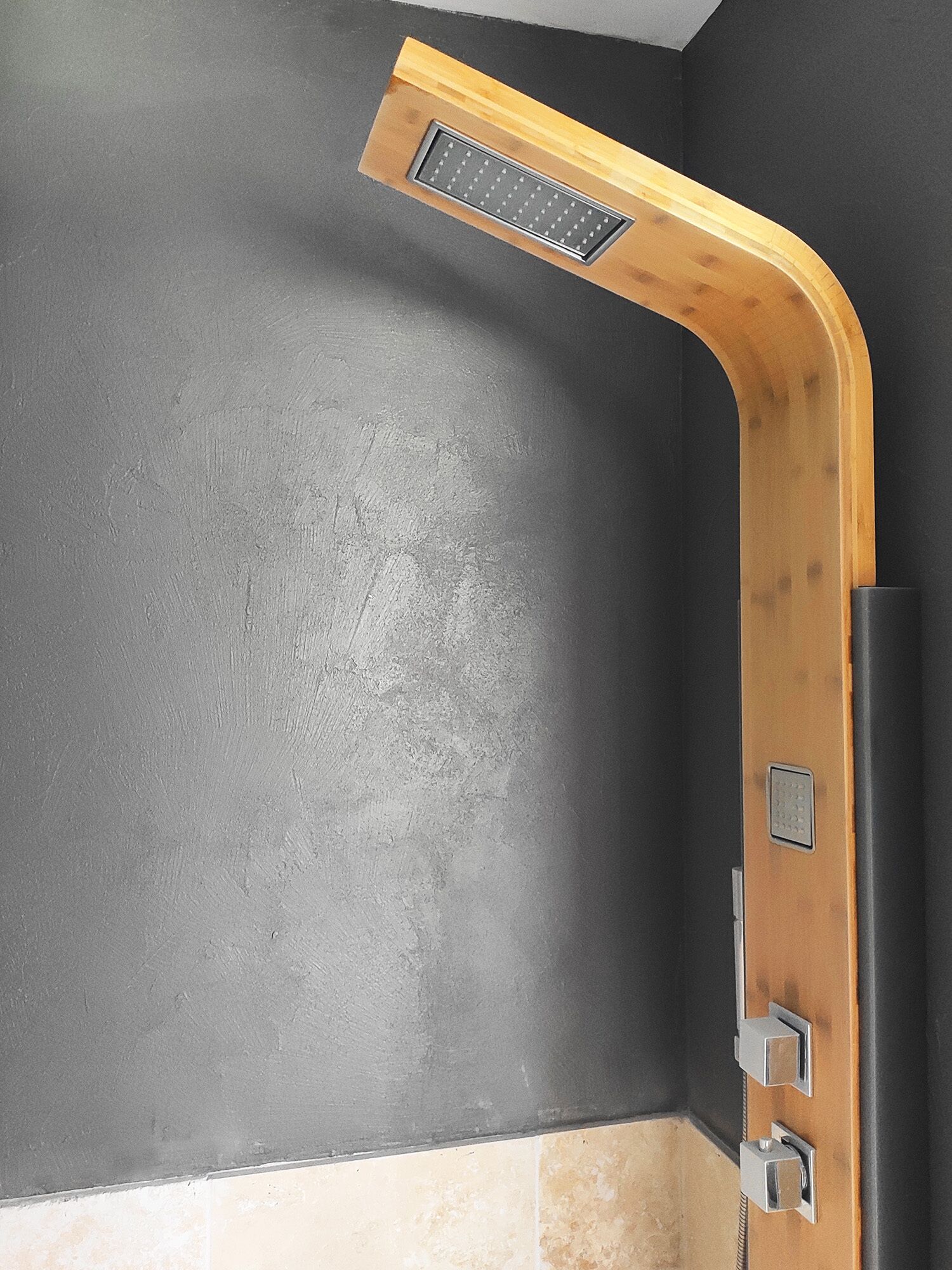 Een hoek van een kamer met een douchecabine van hout en een zwarte wand.